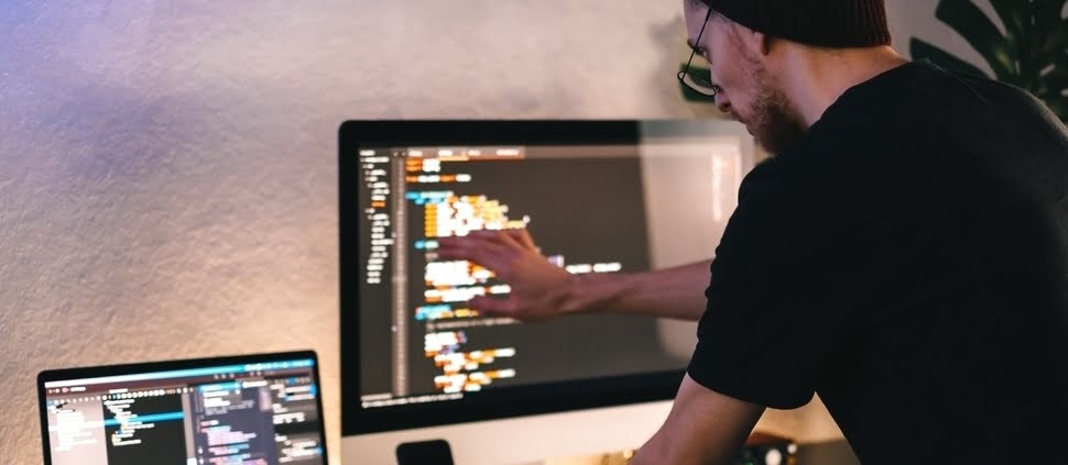 młody programista piszący kod na swoim komputerze