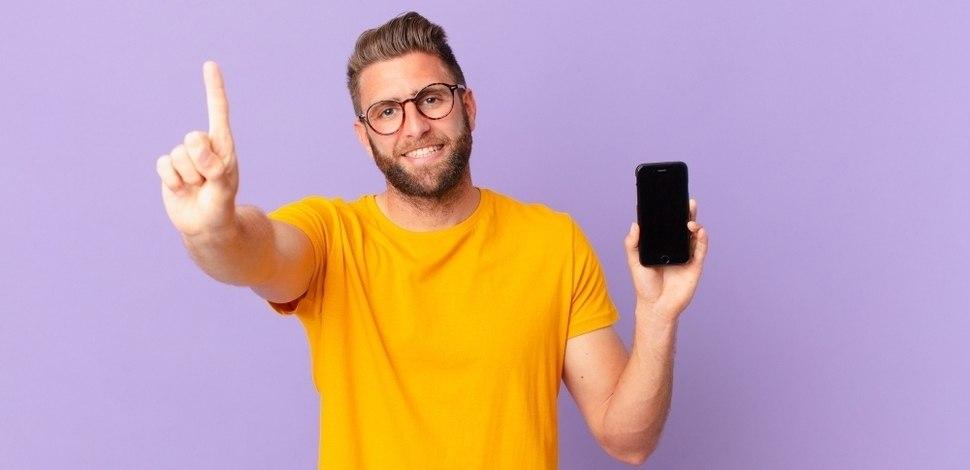 mężczyzna z telefonem w ręku podnoszący rękę - metafora mobile first